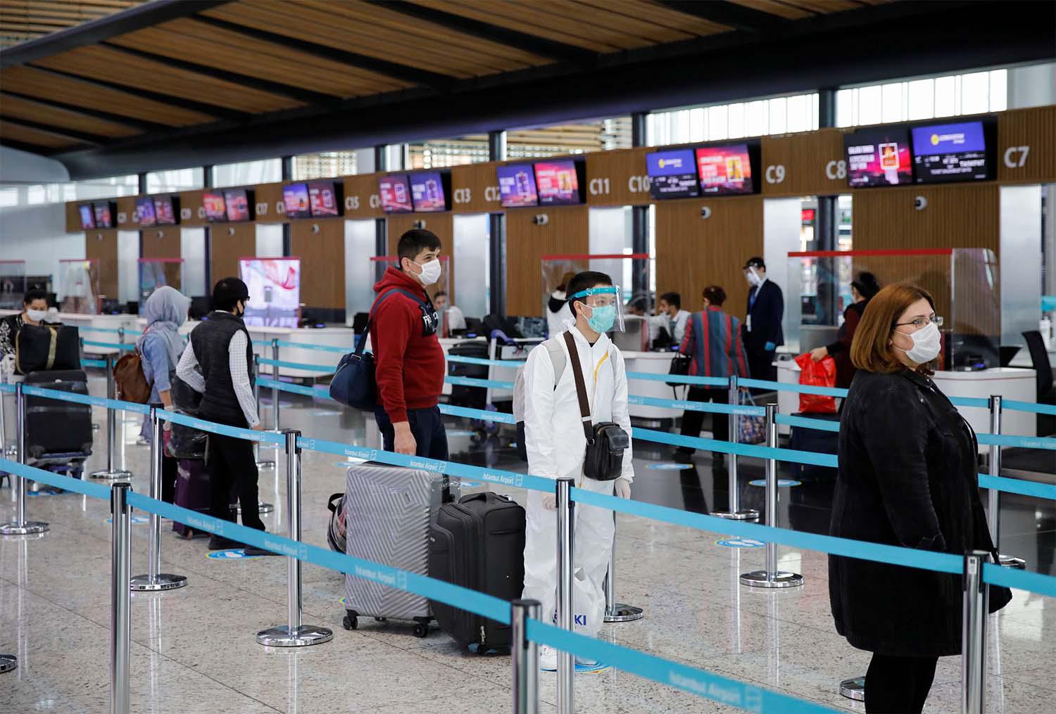 A passenger wearing a protective suit stands in a queue the Istanbul Airport during the first day of resumed domestic flights 