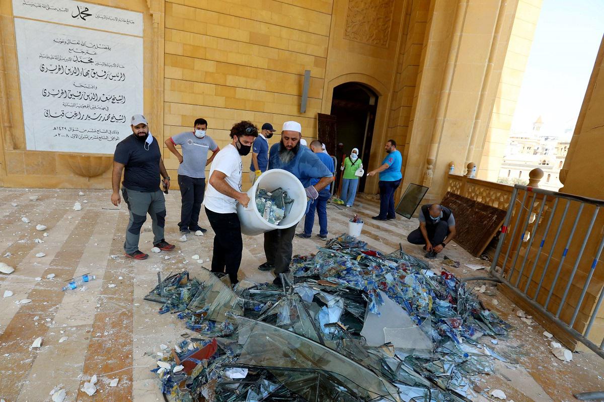 لبنانيون يحمعون زجاجا محطما بعد انفجار بيروت