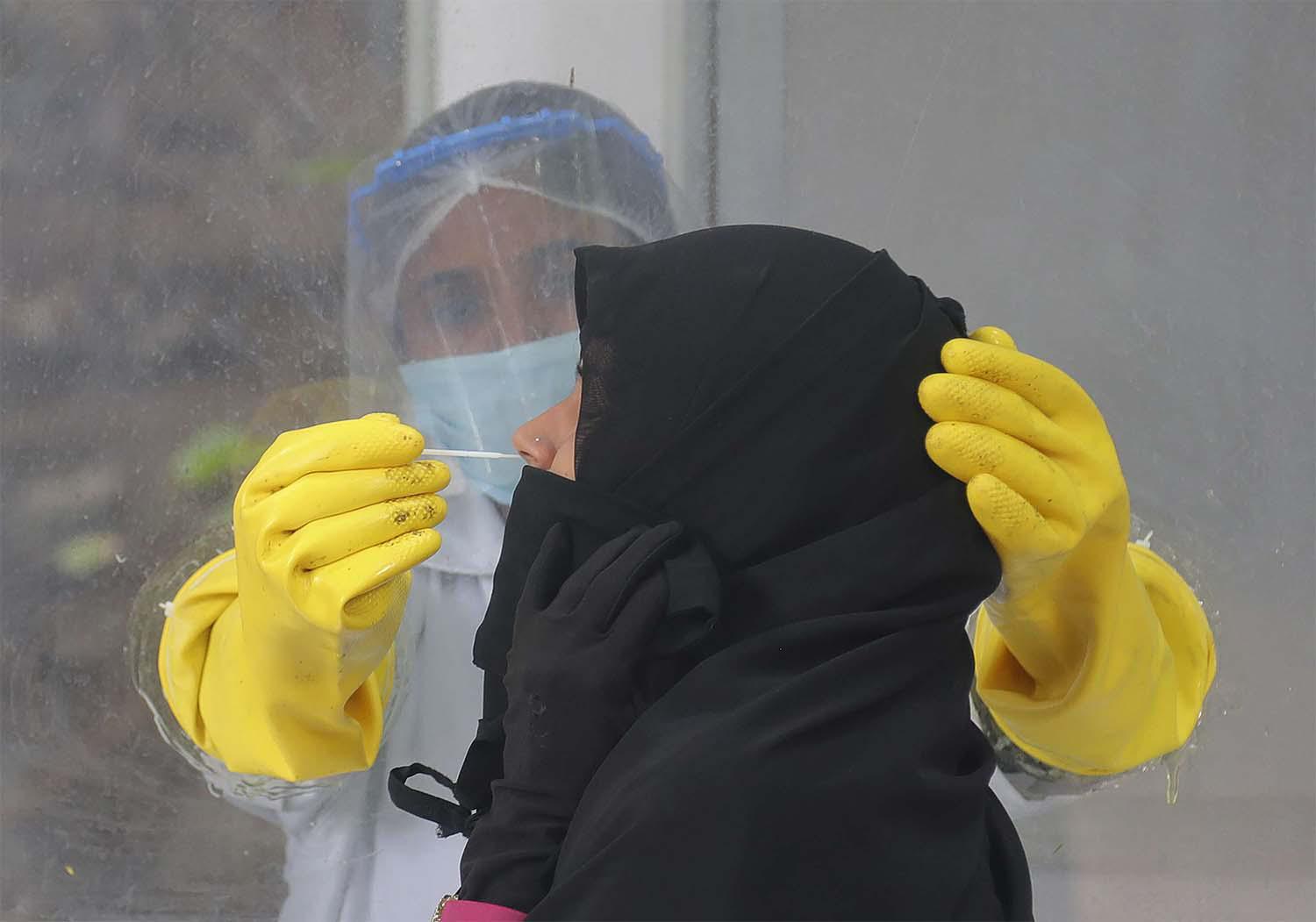 A health worker collects a nasal swab sample to test for COVID-19 in Hyderabad, India