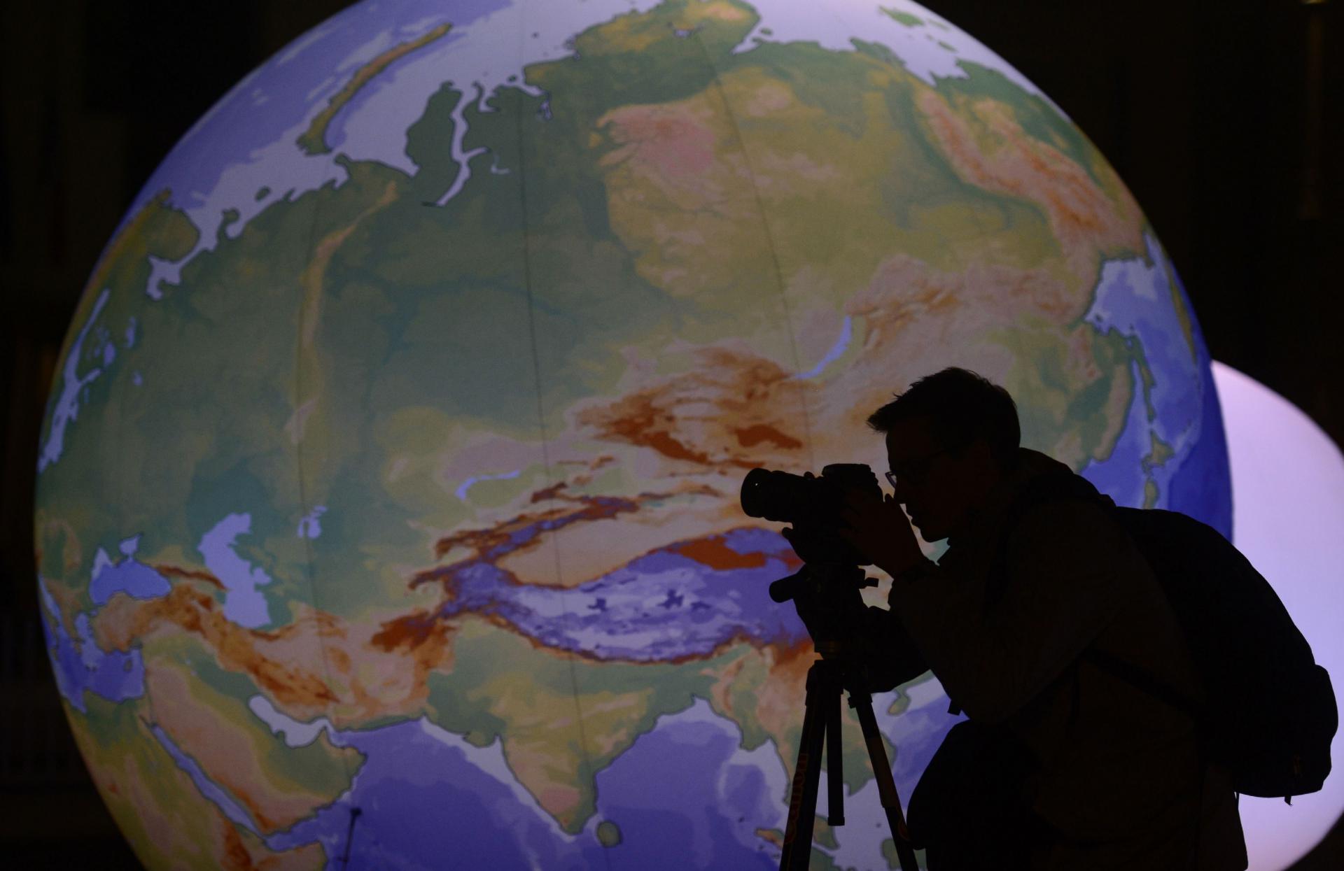 مصور يقف أمام كرة أرضية مضيئة 