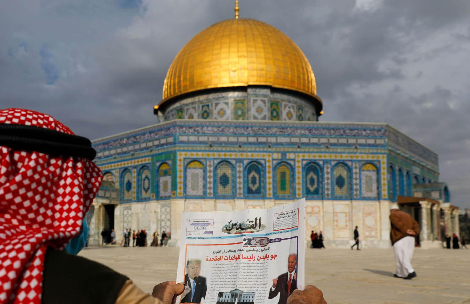 فلسطيني يعرض صحيفة في القدس تنقل خبر فوز بايدن
