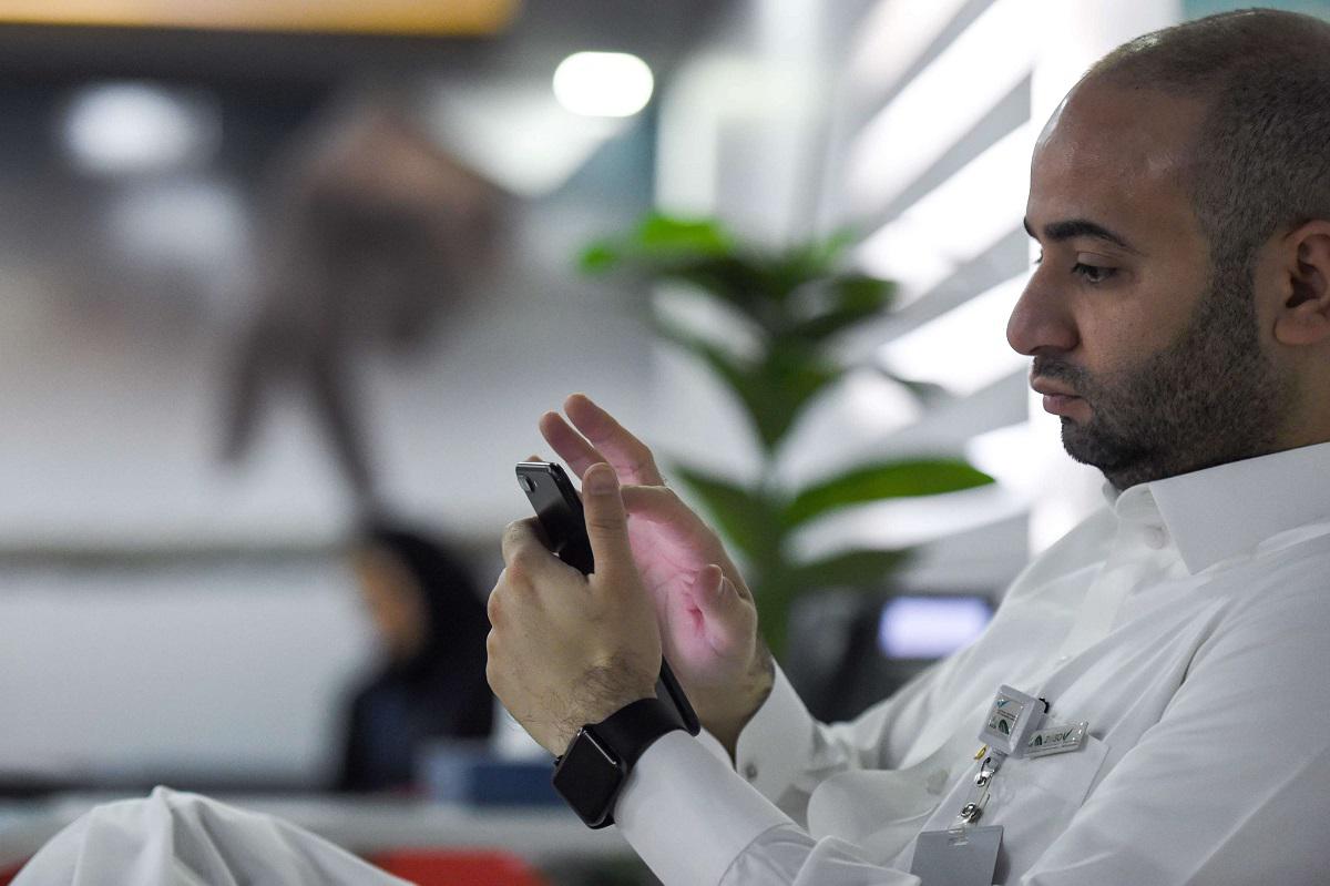 موظف سعودي يتصفح هاتفه في مكتبه بالرياض
