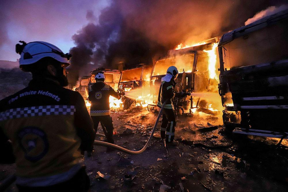 فرق من الدفاع المدني التابعة للمعارضة السورية تحاول اخماد نيران اندلعت في عشرات العربات والشاحنات العسكرية