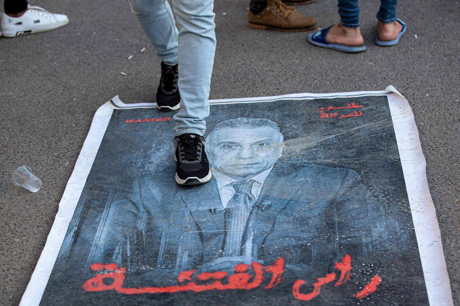 متظاهر من قوات الحشد الشعبي يدوس على صورة مصطفى الكاظمي