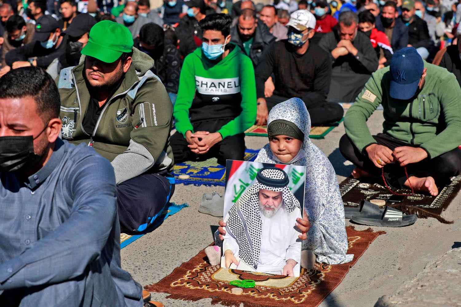 طفلة تحمل صورة الصدر اثناء الصلاة في بغداد