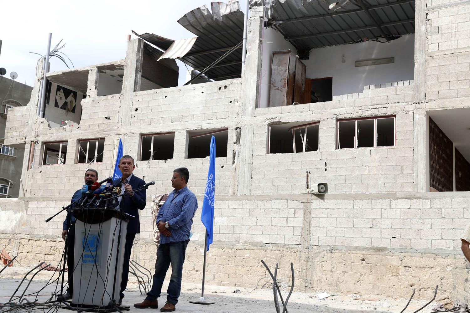 موظفو الاونروا في غزة امام أحد المنازل المدمرة