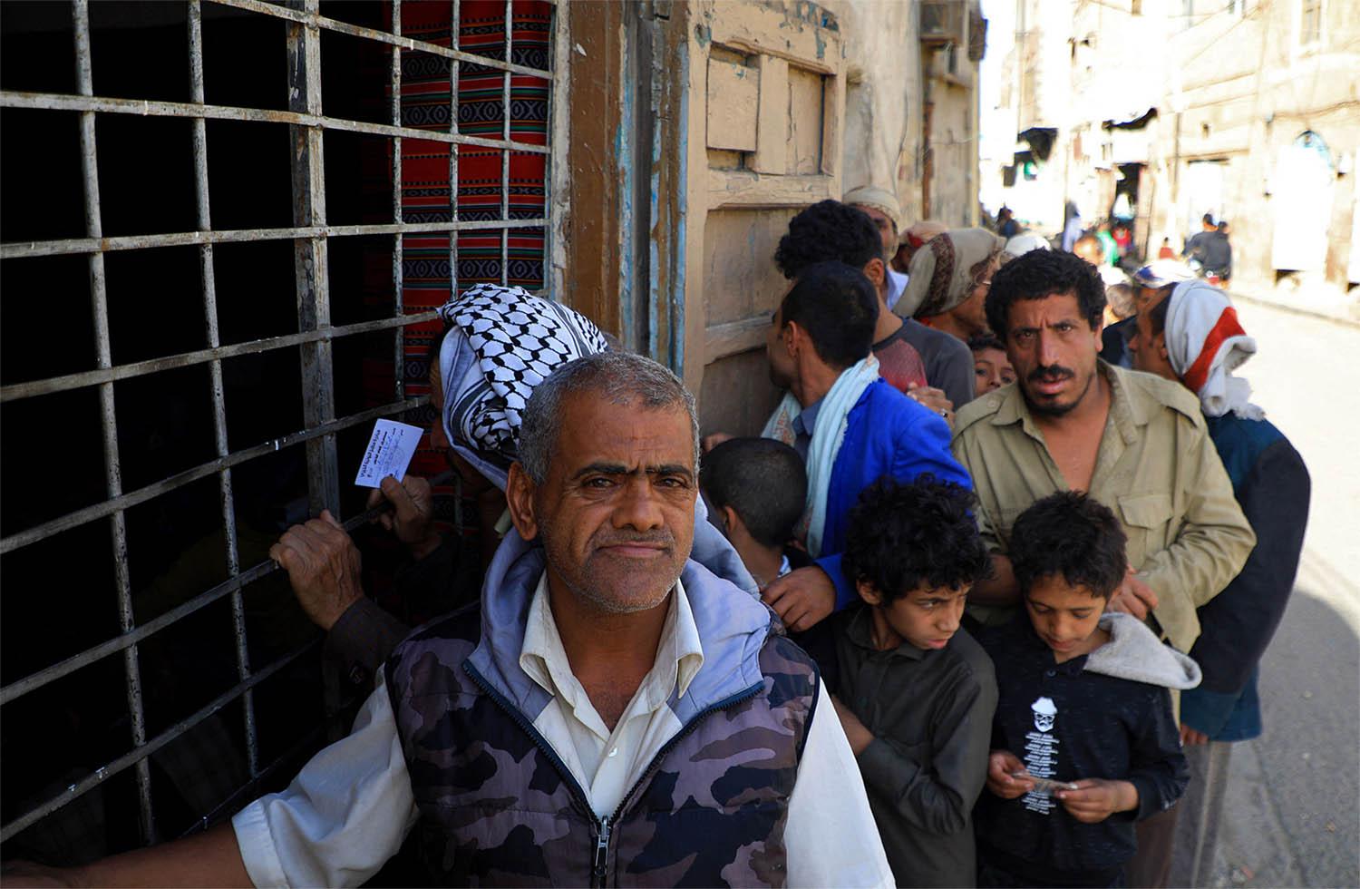 Yemenis wait in line to receive a free fast-breaking "Iftar" meal in Sanaa