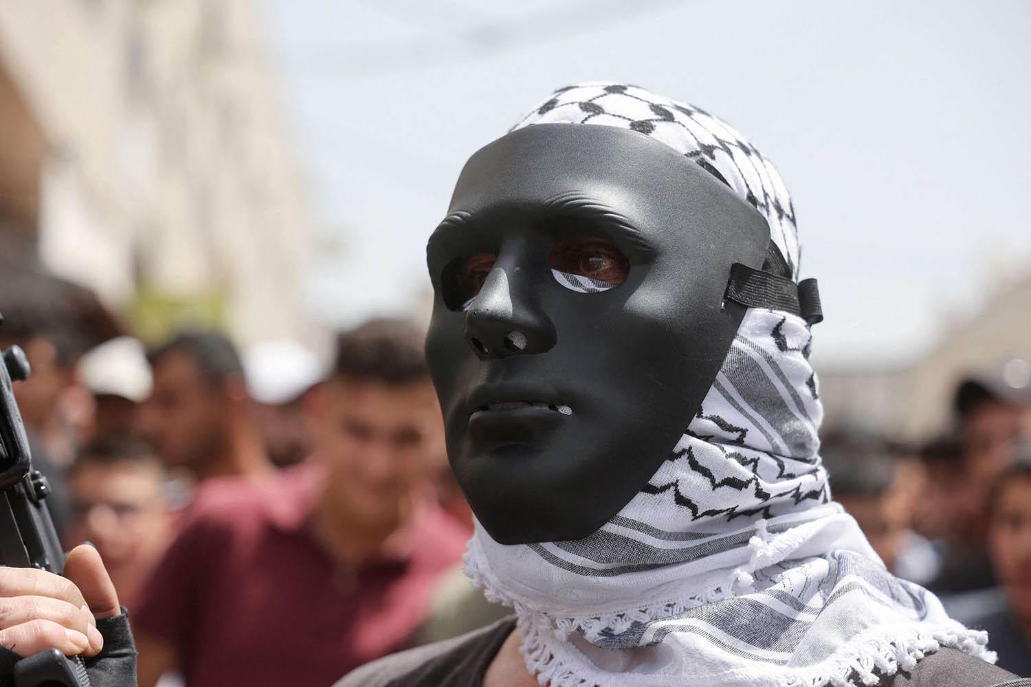 فلسطيني يرتدي قناعا خلال جنازة لناشط فلسطيني في الضفة الغربية
