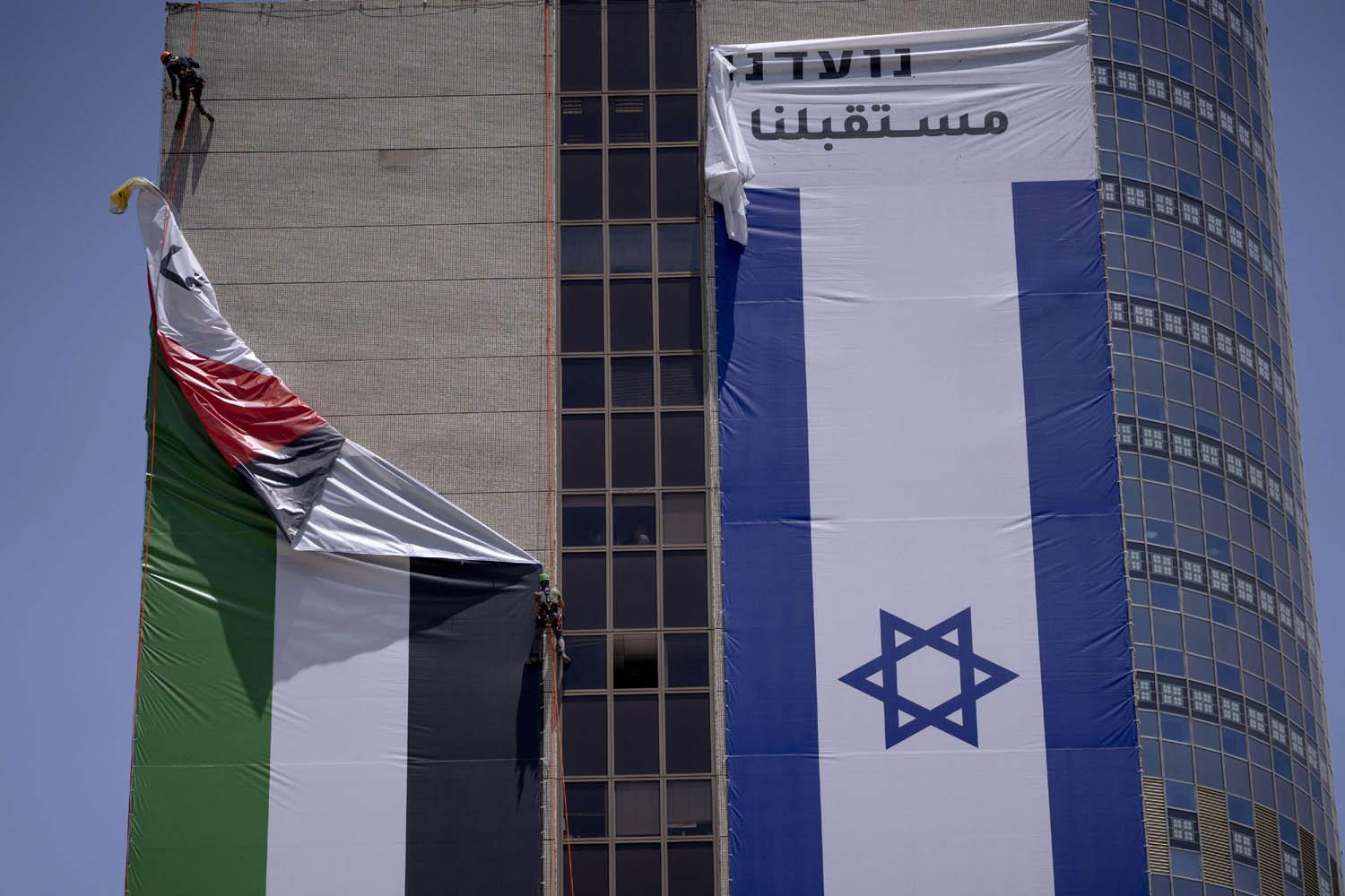 عمال إسرائيليون يزيلون علما فلسطينيا من مبنى في بلدة رامات غان