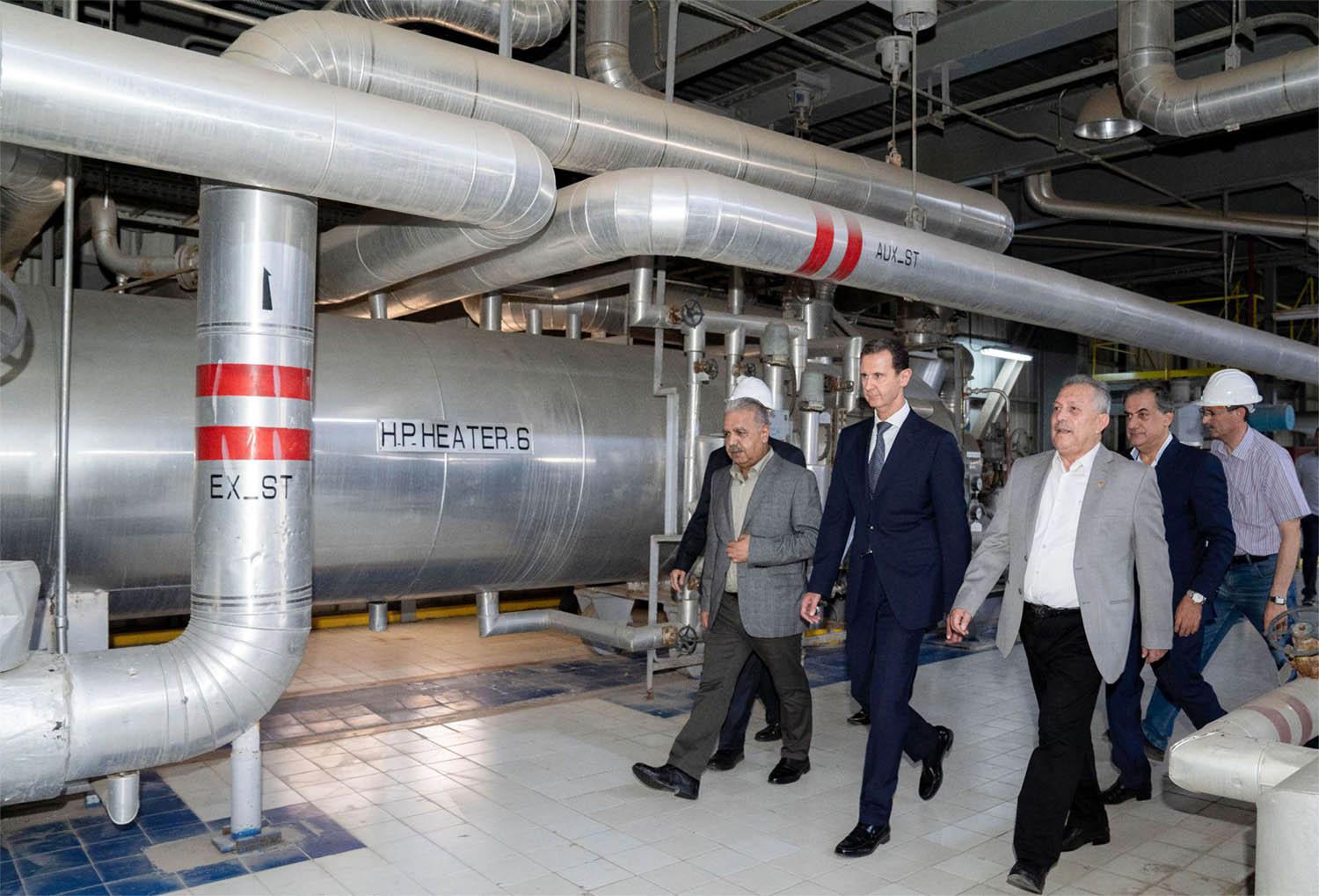 Assad (C) touring a thermal power station in the eastern countryside of Aleppo province