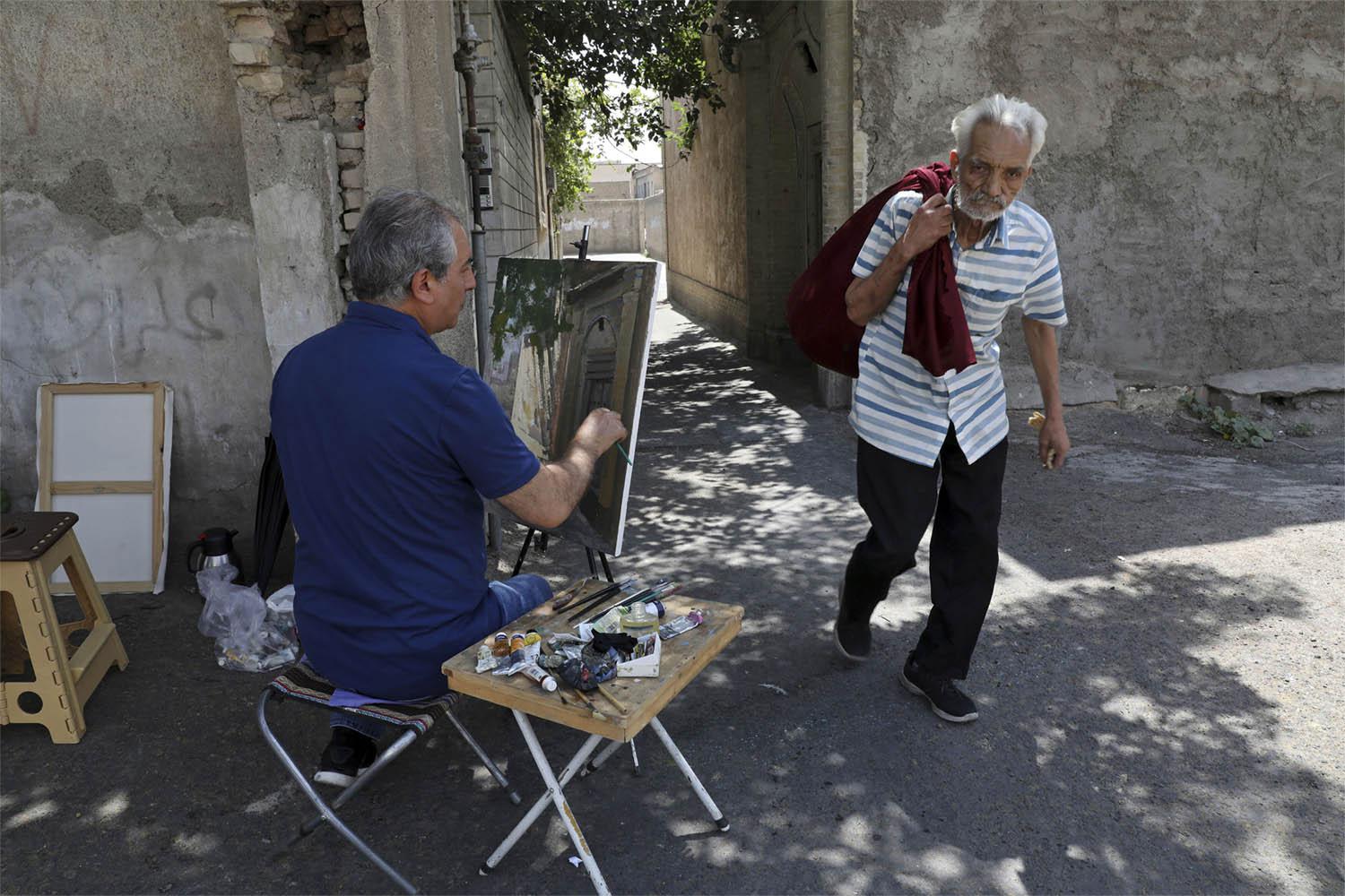 Painter Hassan Naderali paints an old building in the historic neighborhood of Oudlajan, in Tehran