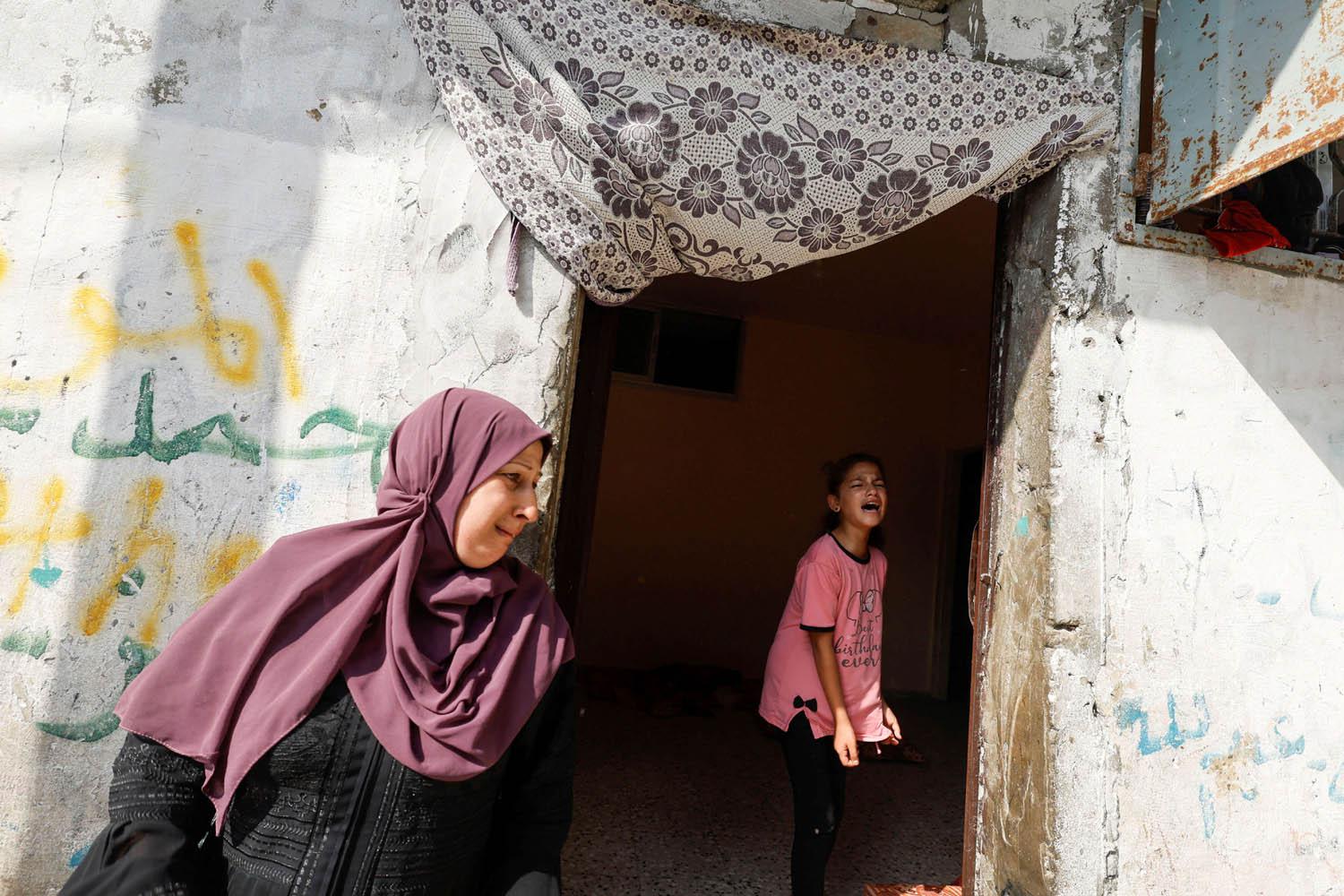عائلة فلسطينية تبكي الدمار الذي احدثه القصف الاسرائيلي