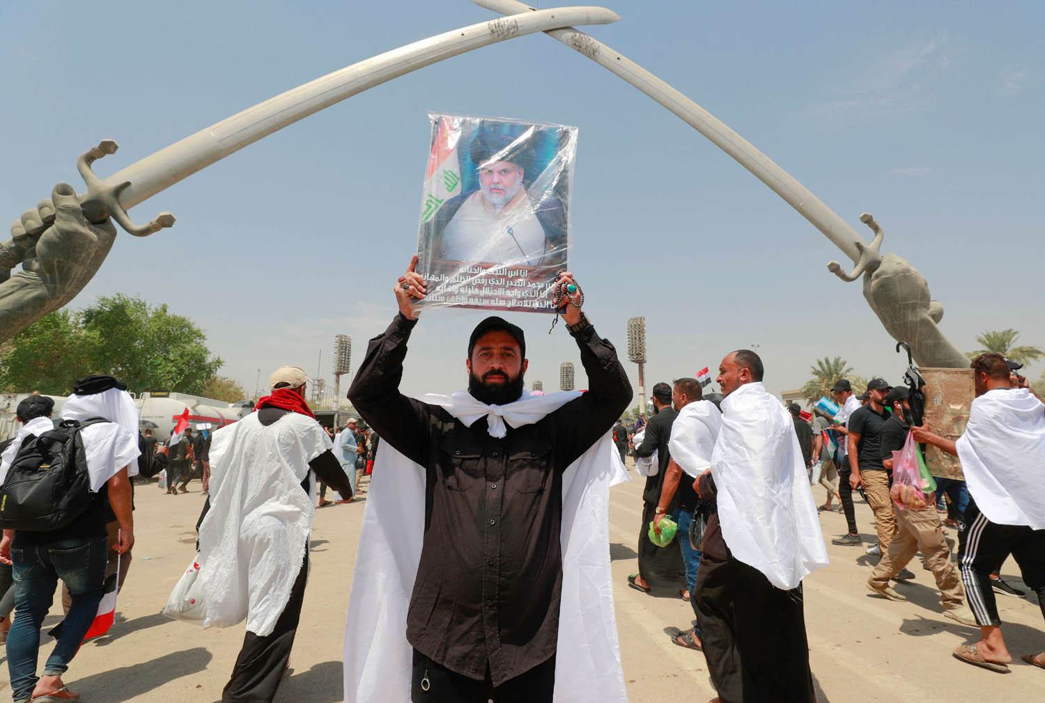 ناشط من الصدريين يرفع صورة مقتدى الصدر في ساحة الاحتفالات الكبرى وسط بغداد