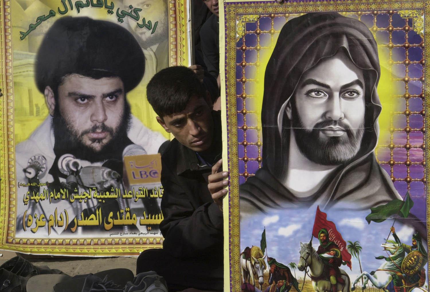 متظاهر من التيار الصدري يرفع صورة متخيلة للإمام الحسين وصورة لمقتدى الصدر