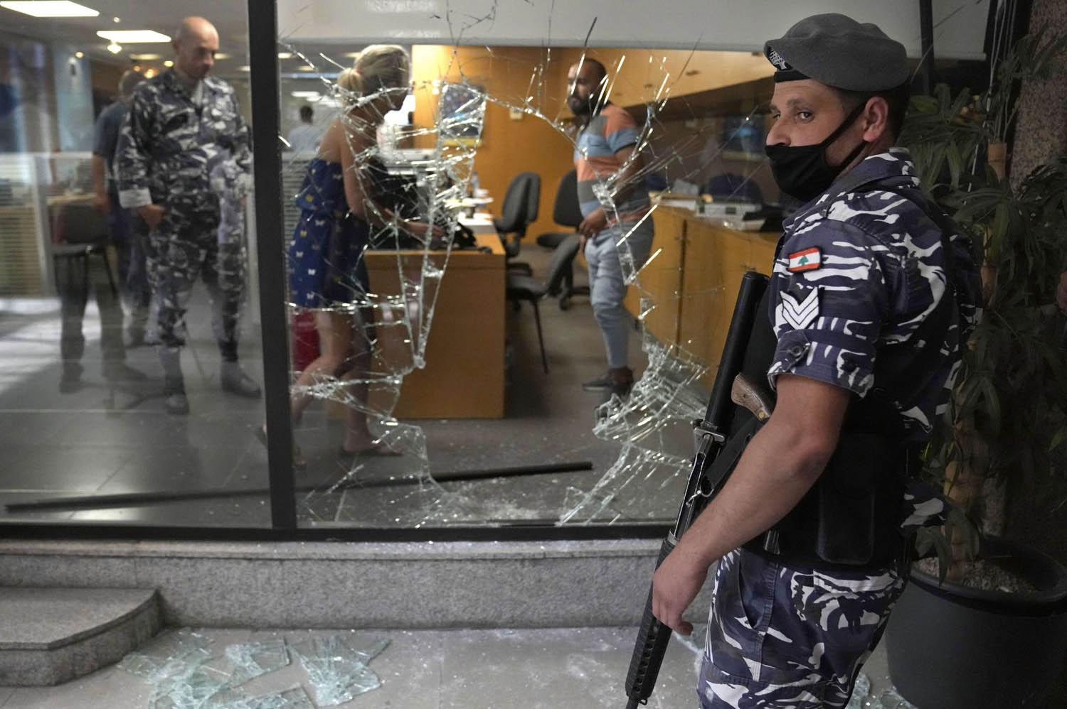 شرطي لبناني يحرس ثغرة في الواجهة الزجاجية لمصرف في بيروت