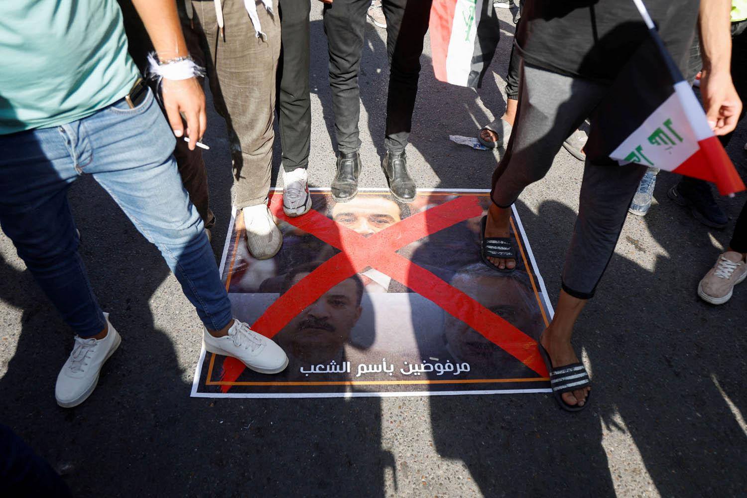 محتجون عراقيون يدوسون على صور لرئيس البرلمان العراقي محمد الحلبوسي وعلى رئيس الوزراء المكلف محمد شياع السوداني