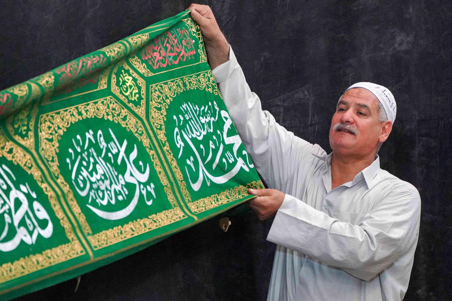 عراقي يرفع راية تحمل اسم الرسول محمد وعائلته علي وفاطمة
