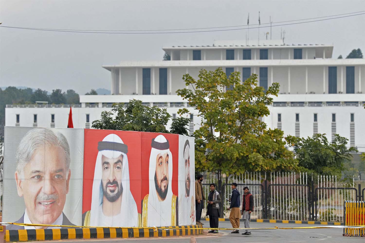 Workers arrange portraits of UAE President Sheikh Mohamed bin Zayed al-Nahyan (C) and Pakistan Prime Minister Nawaz Sharif (L) along the constitution avenue in Islamabad 