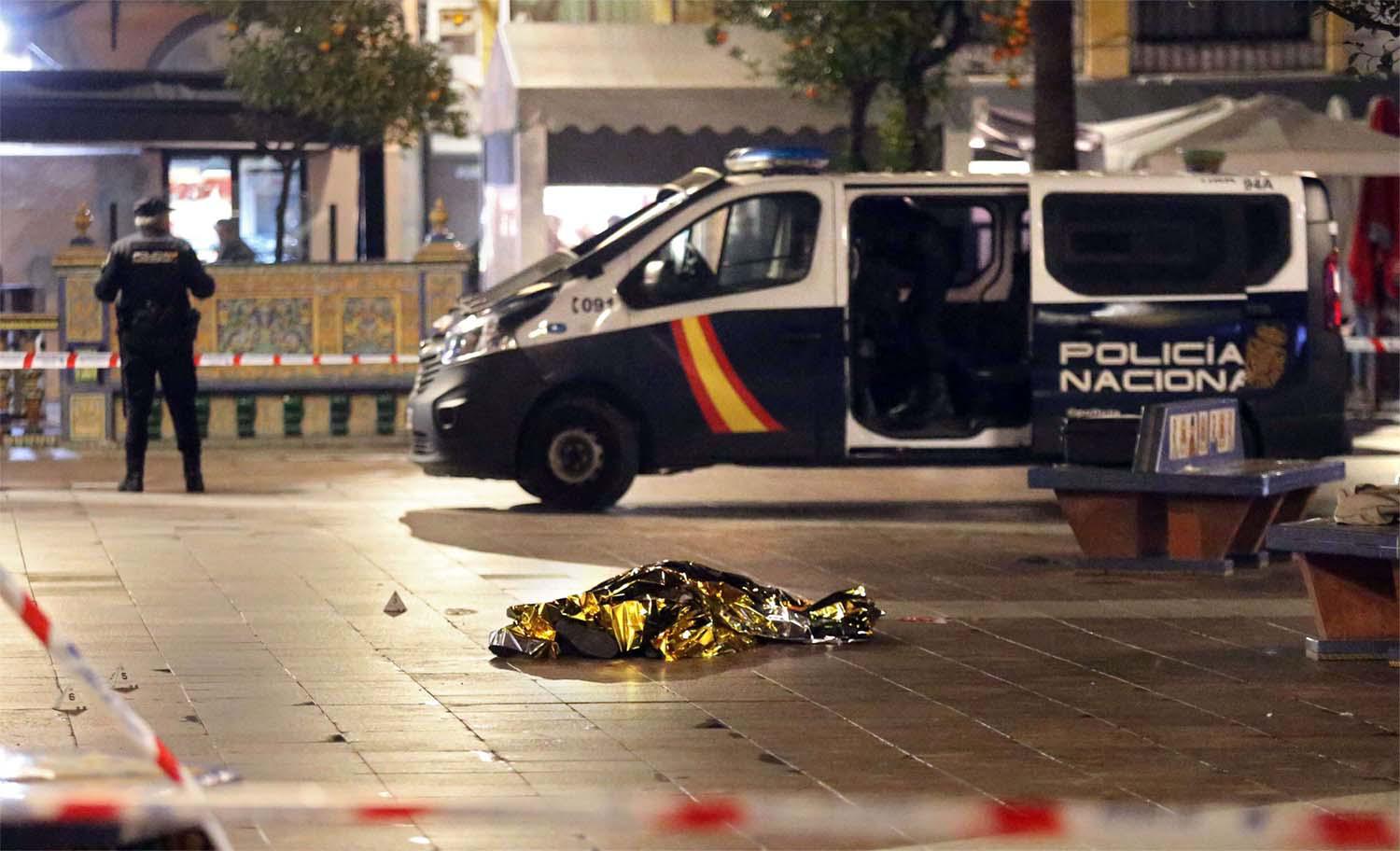 The body of a dead man lays on the ground as police secure the area in Algeciras, southern Spain