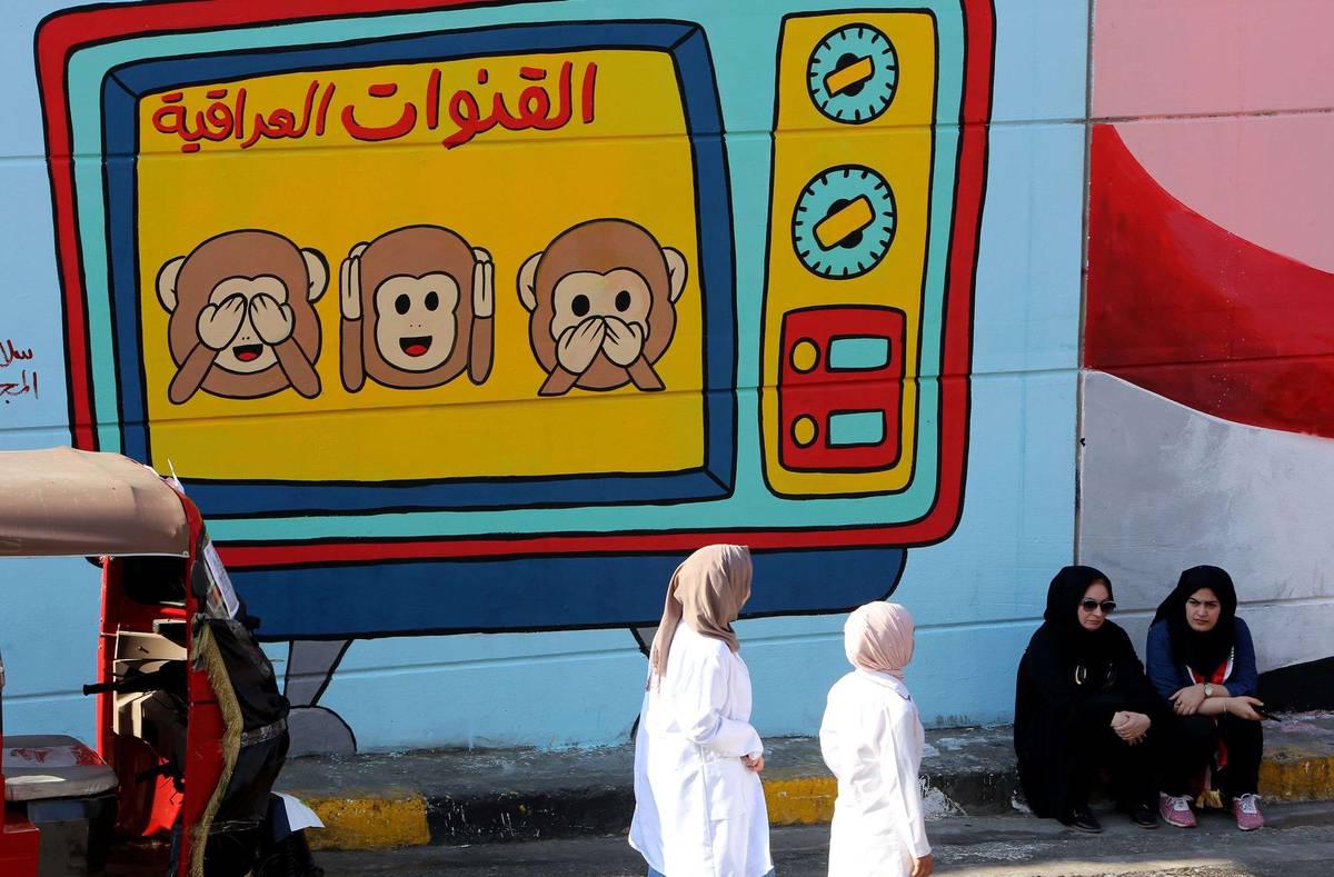 عراقيات بجانب جدارية تنتقد القنوات العراقية