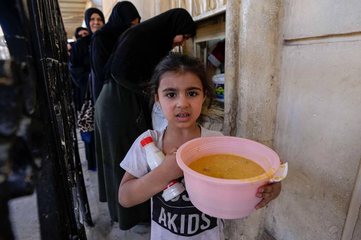 طفلة عراقية تحمل شورية يوزعها مسجد عبدالقادر الكيلاني وسط بغداد