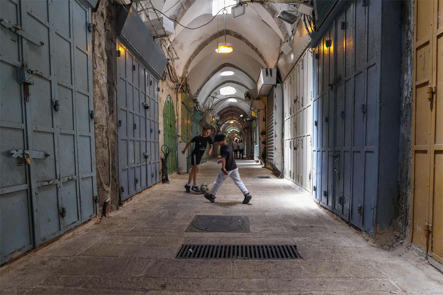 Youths play football near shuttered shops during a Palestinian general strike in Jerusalems old city