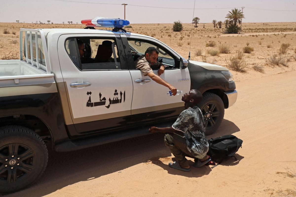 شرطي ليبي يسكب ماء في فم مهاجر أفريقي على الحدود الليبية التونسية