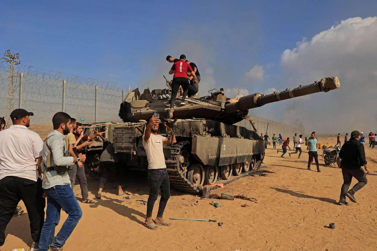 فلسطينيون يأخذون صورا بجانب دبابة إسرائيلية على الحدود مع غزة