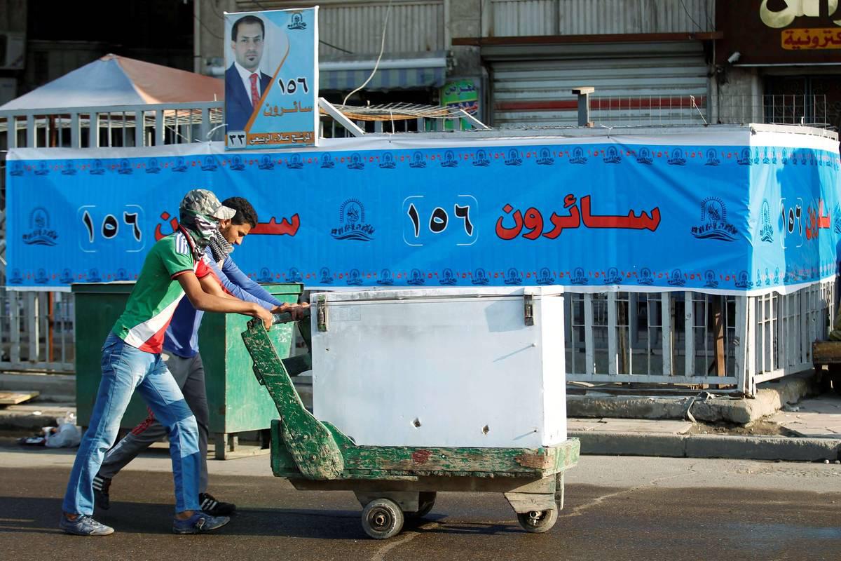 عراقيان يمران بجانب ملصق انتخابي عراقي