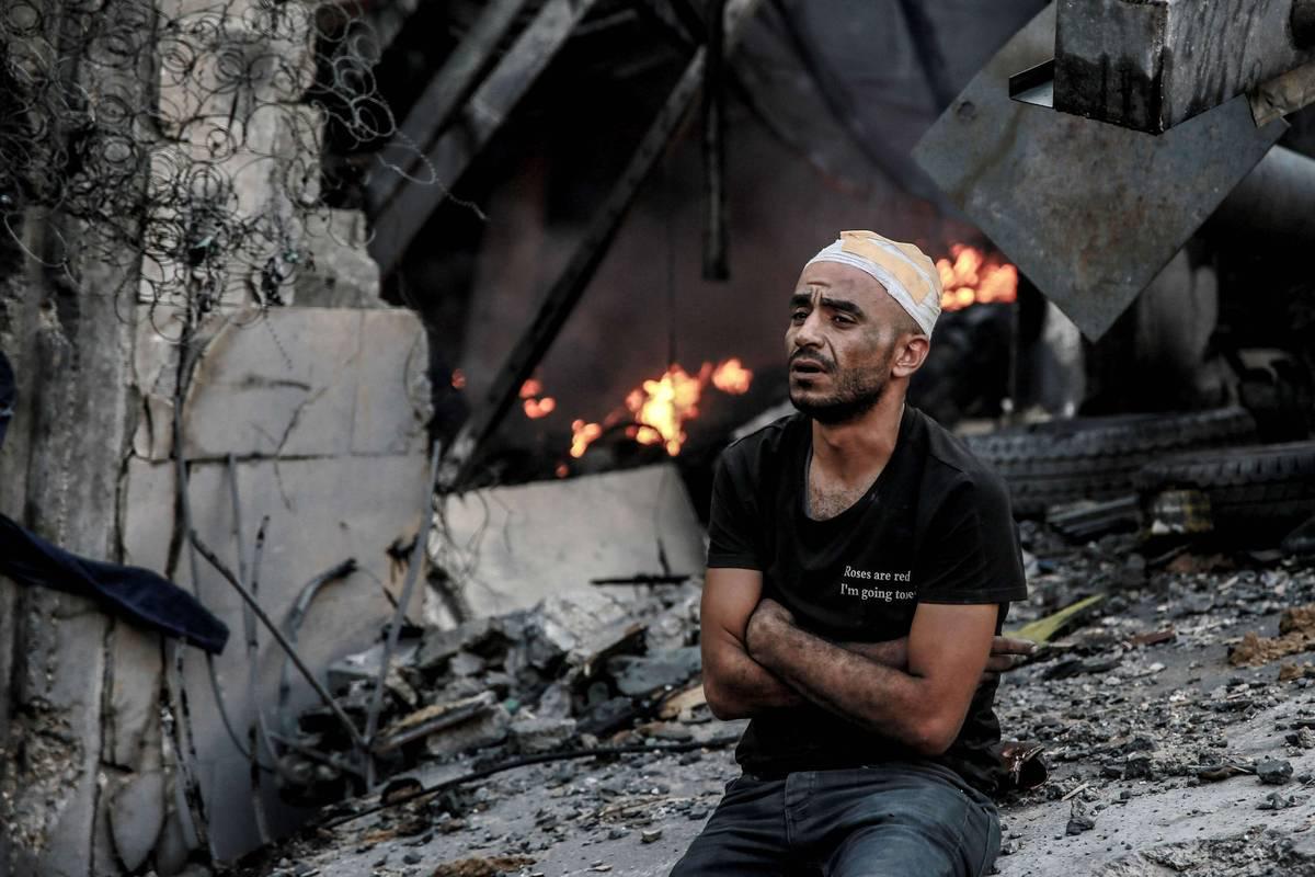 فلسطيني جريح جنب بيته المدمر في غزة بعد قصف إسرائيلي