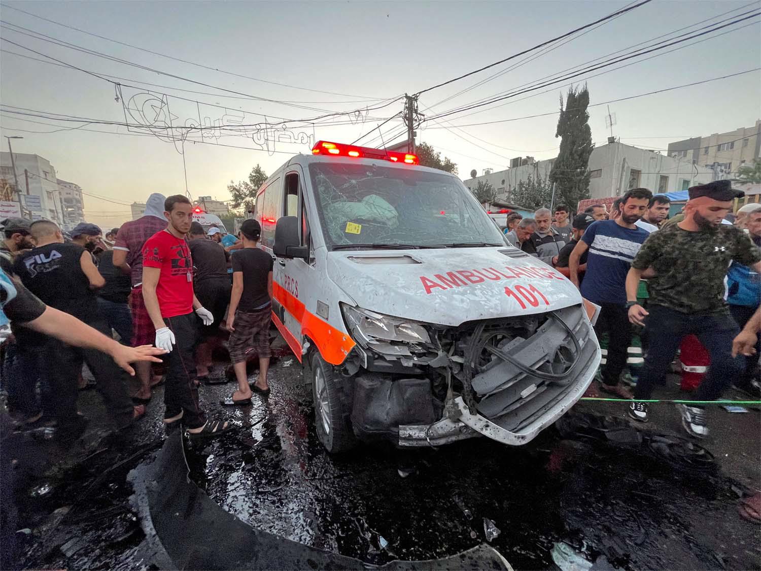 Palestinians check the damages after a convoy of ambulances was hit, at the entrance of Shifa hospital in Gaza City