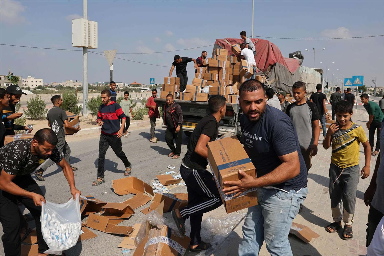 Gazans unpack boxes of humanitarian aid from a truck that entered the southern Gaza Strip from Egypt