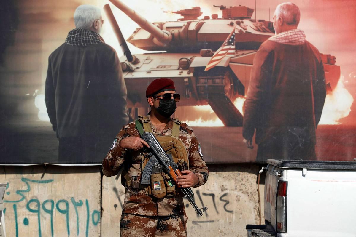 جندي عراقي أمام جدارية لدبابة أميركية وقاسم سليماني وأبومهدي المهندس