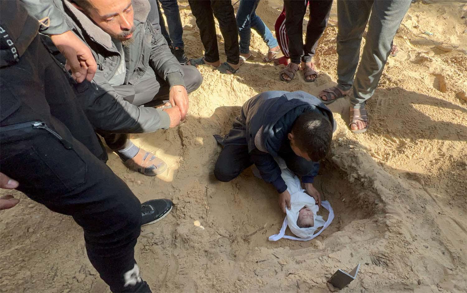 People bury the body of a Palestinian child killed in an Israeli strike, at the Nasser hospital premises 