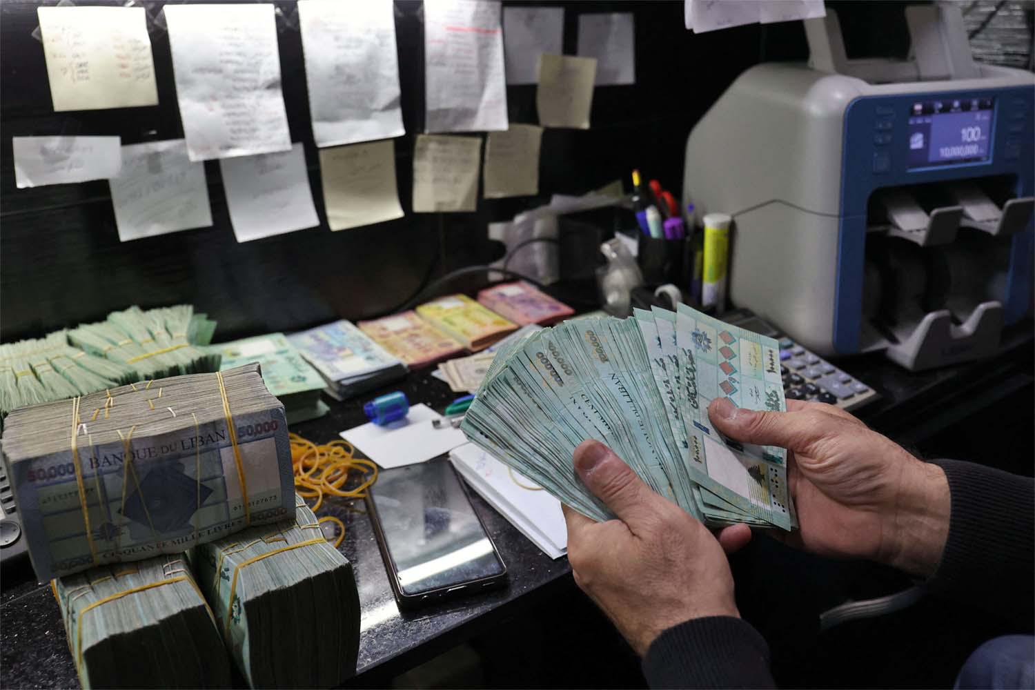 A man handles Lebanese pound bills at a currency exchange office in Beirut