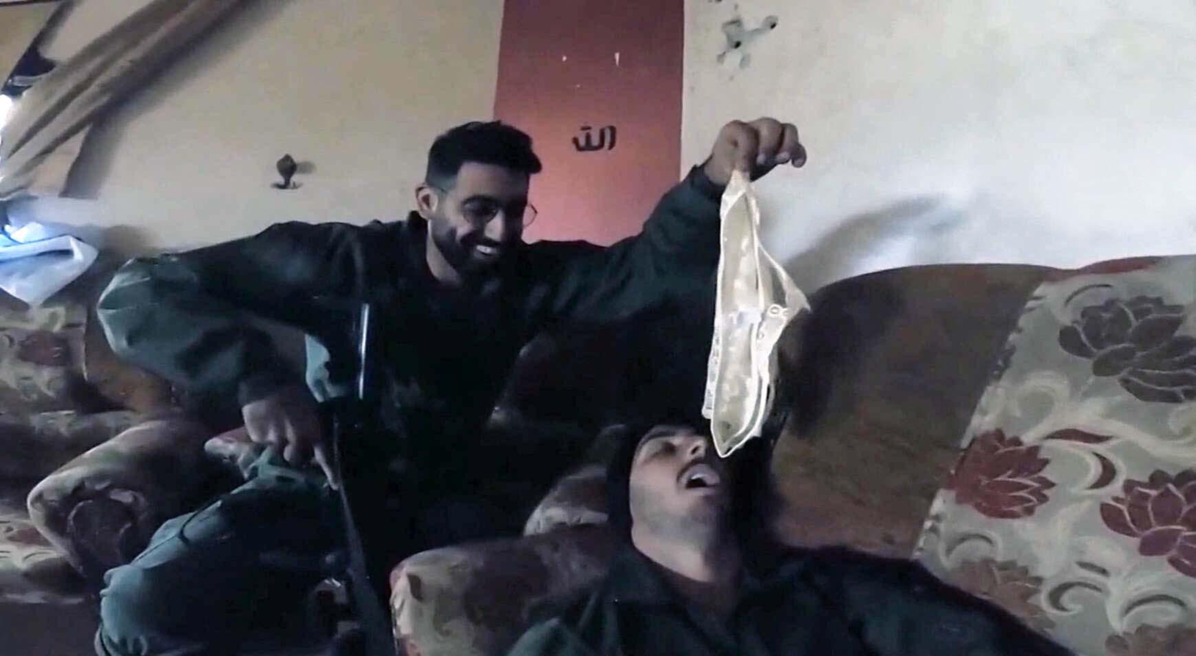 An Israeli soldier dangling white satin underwear over the open mouth of a comrade lying on a sofa
