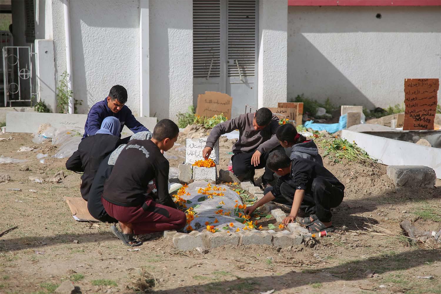Palestinian mourners gather around a fresh grave at the grounds of the Baptist Hospital