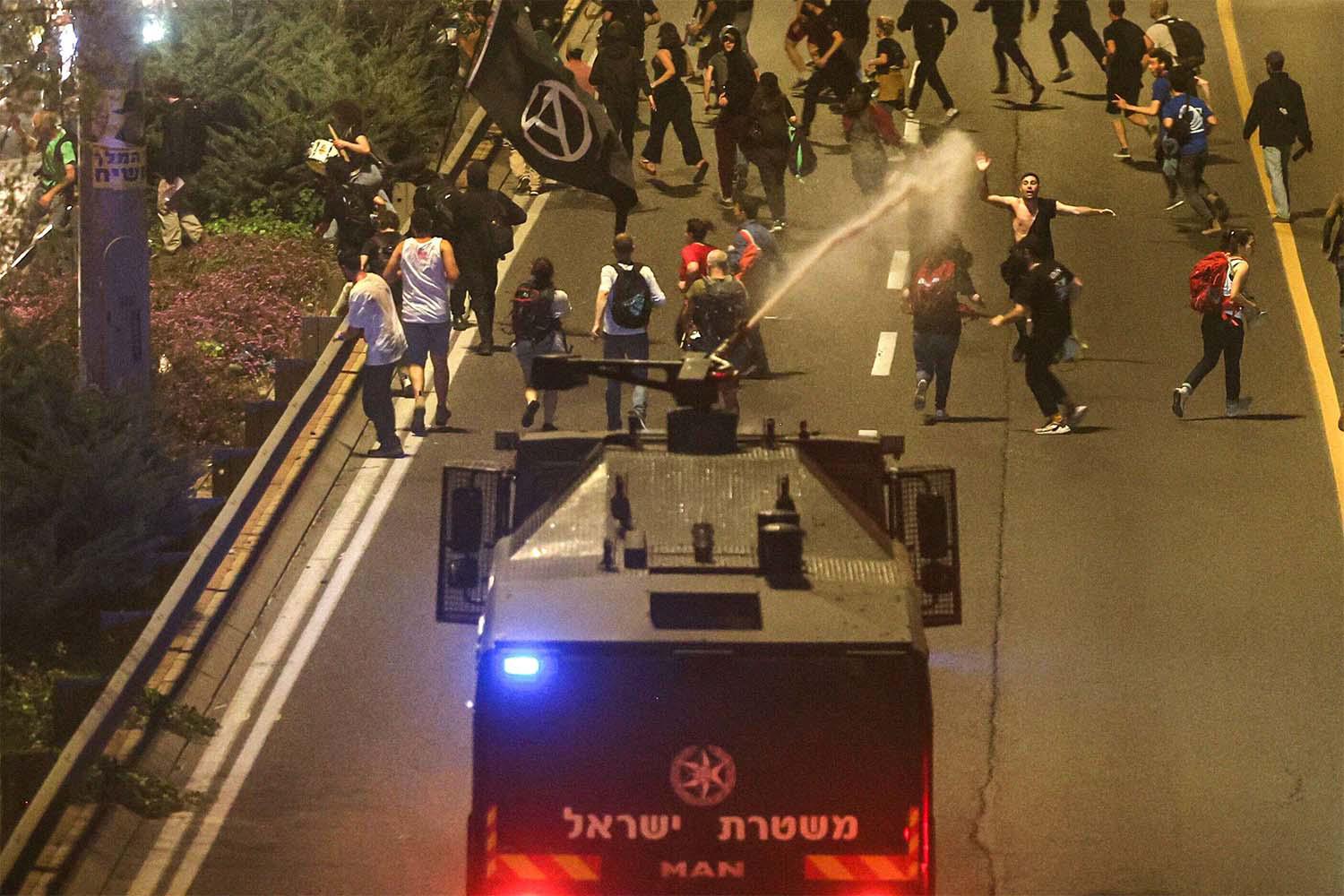 Israeli police disperse demonstrators with a water canon during a protest against Netanyahu's government 