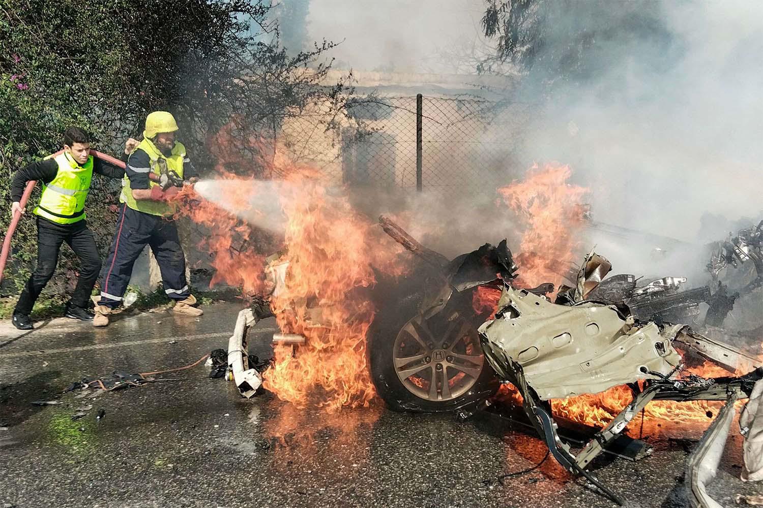 Firefighters douse a burning car after it was hit in the Israeli drone attack