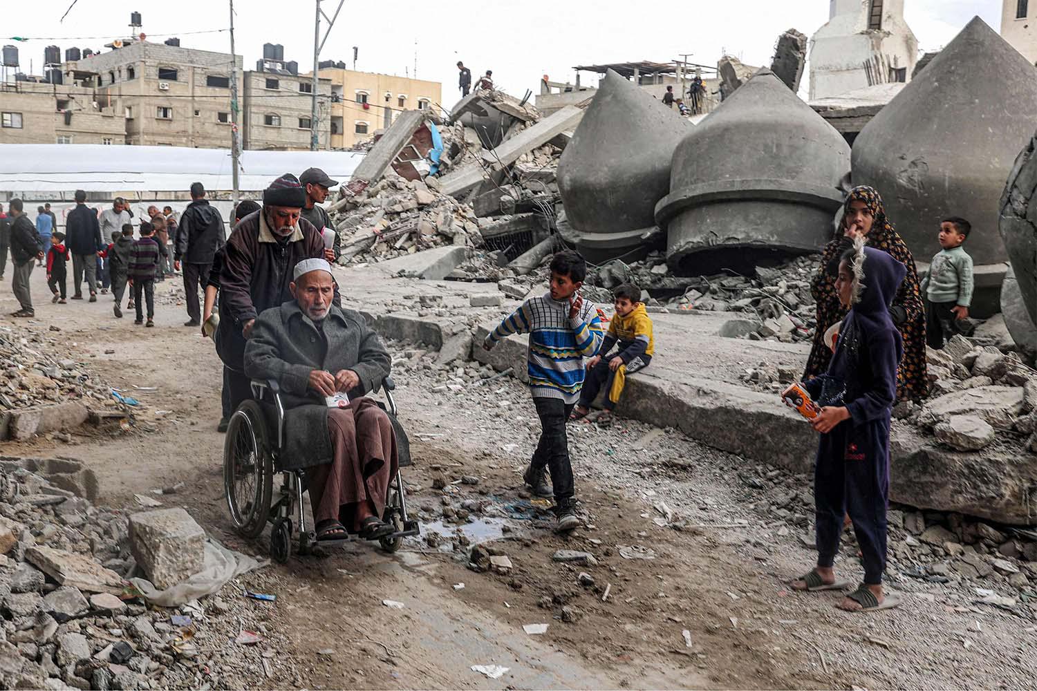 Gazans walk past the rubble of Al-Faruq Mosque that was destroyed during Israeli bombardment in Rafah