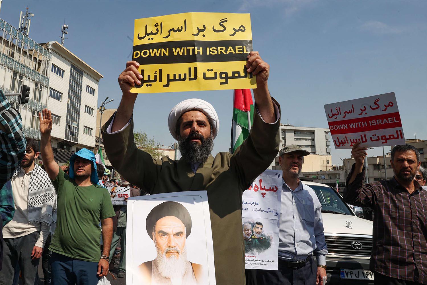 An Iranian Shiite Muslim cleric raises a placard during an anti-Israel demonstration after the Friday noon prayer in Tehran