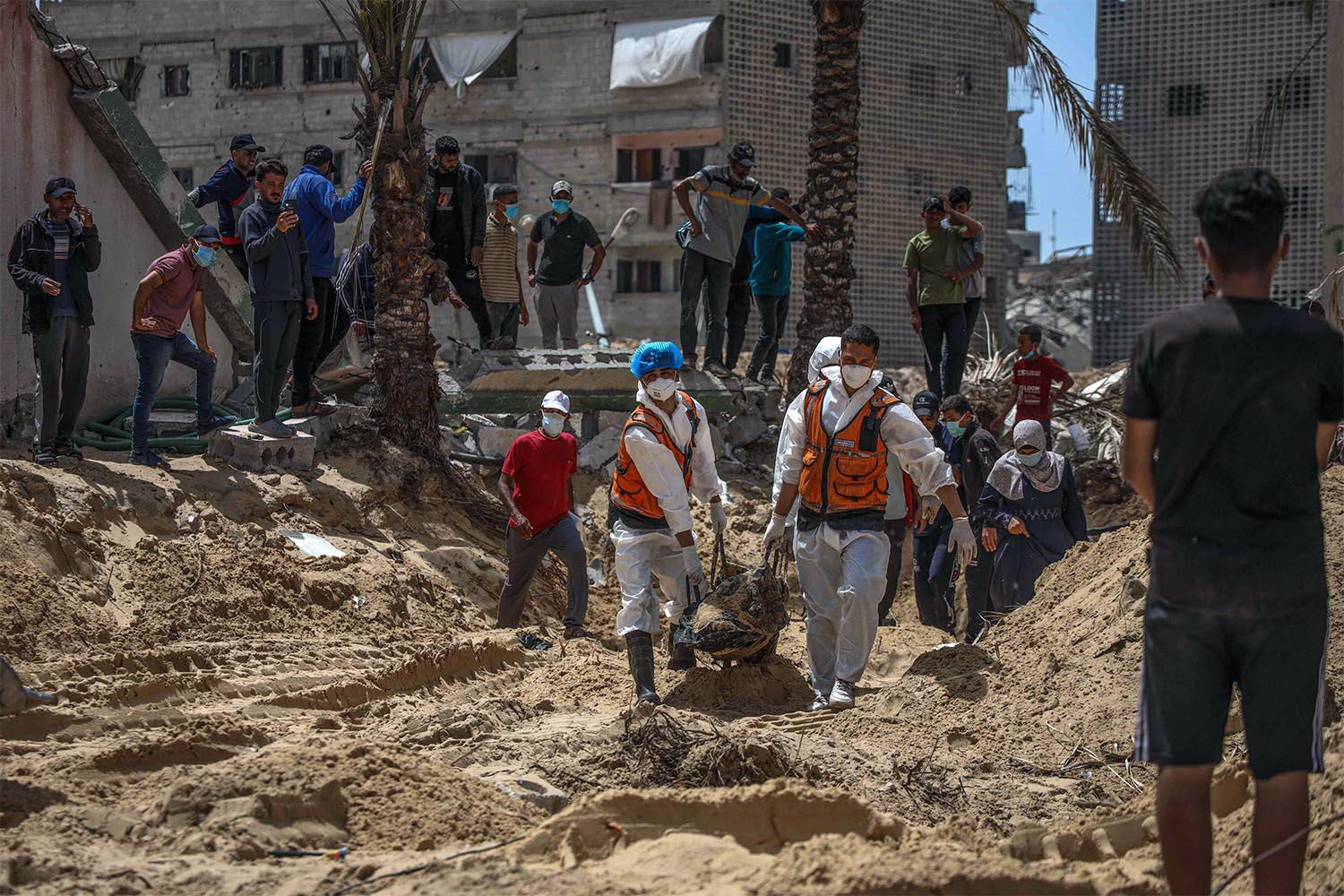 People and health workers unearth bodies found at Nasser Hospital in Khan Yunis in the southern Gaza Strip