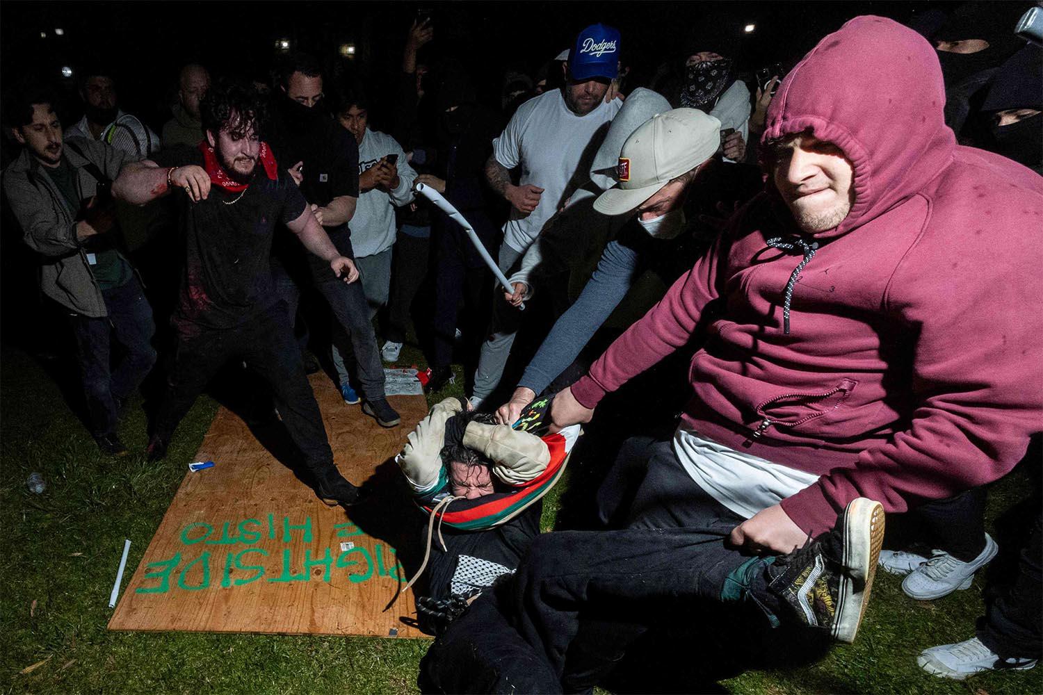 Counter-protesters wielding sticks or poles attacked wooden boards being held up as a makeshift barricade to protect pro-Palestinian protesters