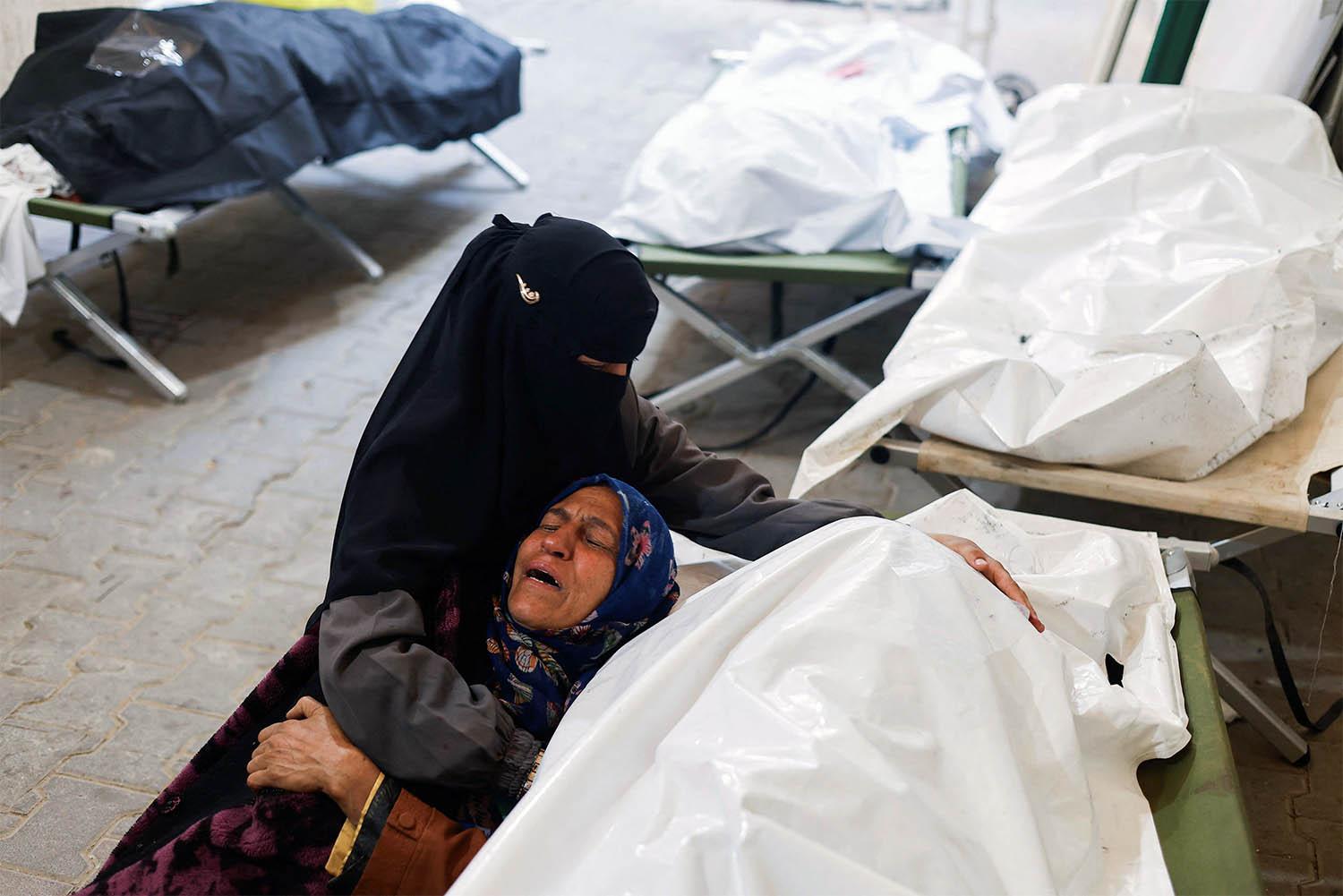 Women mourn next to the bodies of Palestinians killed in Israeli strikes on Rafah