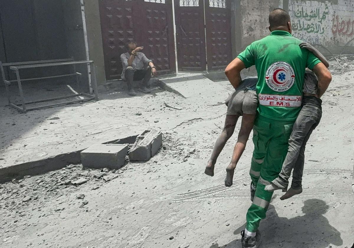 مسعف فلسطيني يحمل طفلين فلسطينيين من موقع قصف إسرائيلي لغزة