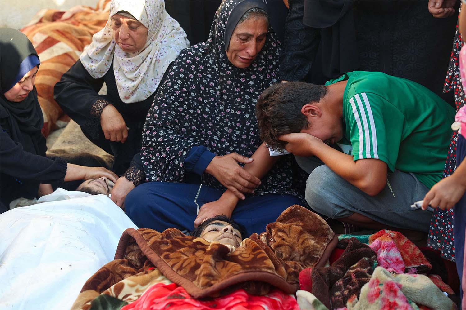 Relatives mourn over the body of a man killed in an Israeli airstrike at a UN school housing displaced Palestinians in Nuseirat