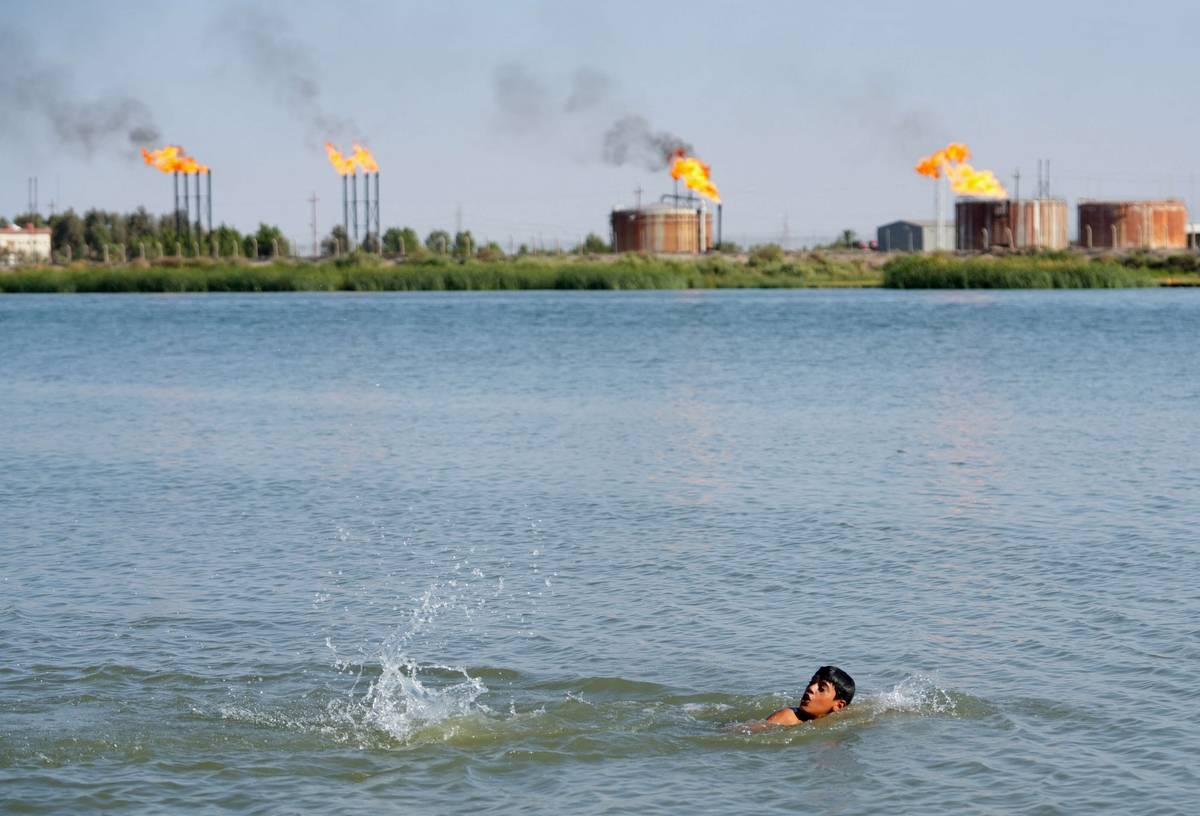 طفل عراقي يسبح بالقرب من منشآت نفطية في حقول نهر بن عمر بالبصرة