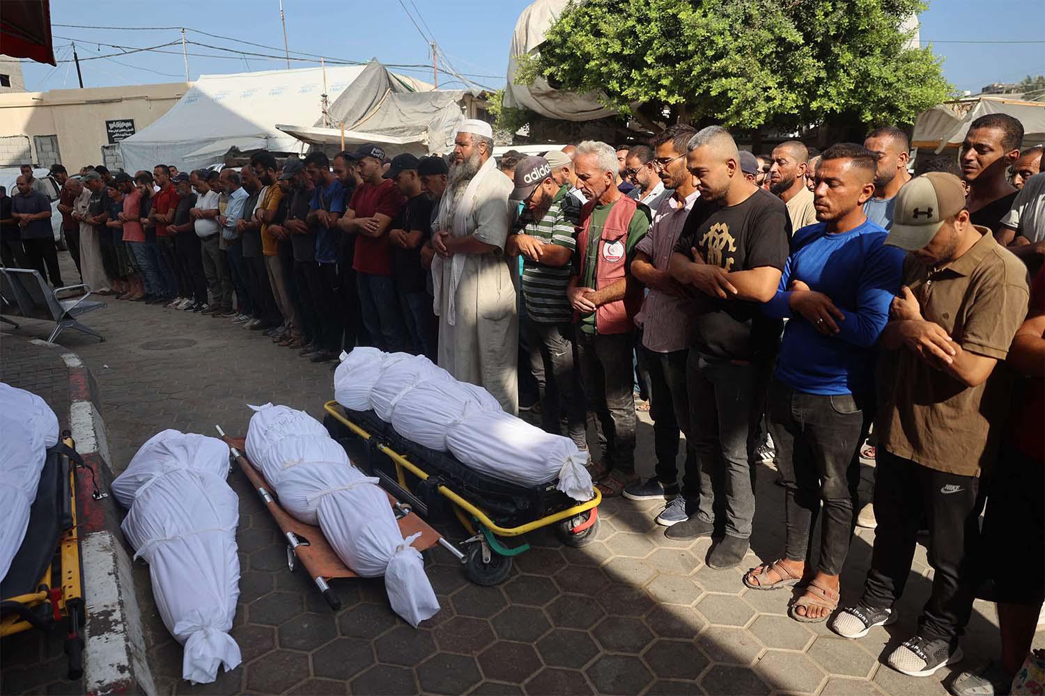 Palestinians mourn over the bodies of victims of Israeli bombardment in Deir el-Balah