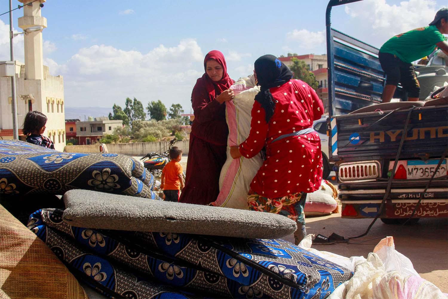 Syrian refugees load their belongings on a truck as they prepare to leave the southern Lebanese village of Wazzani
