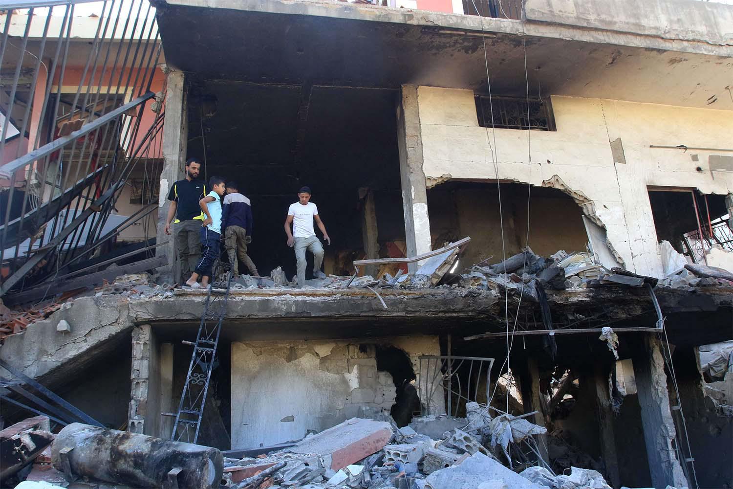 People inspect the debris at the site of an overnight Israeli strike on a house in the southern Lebanese village of Akbiyeh